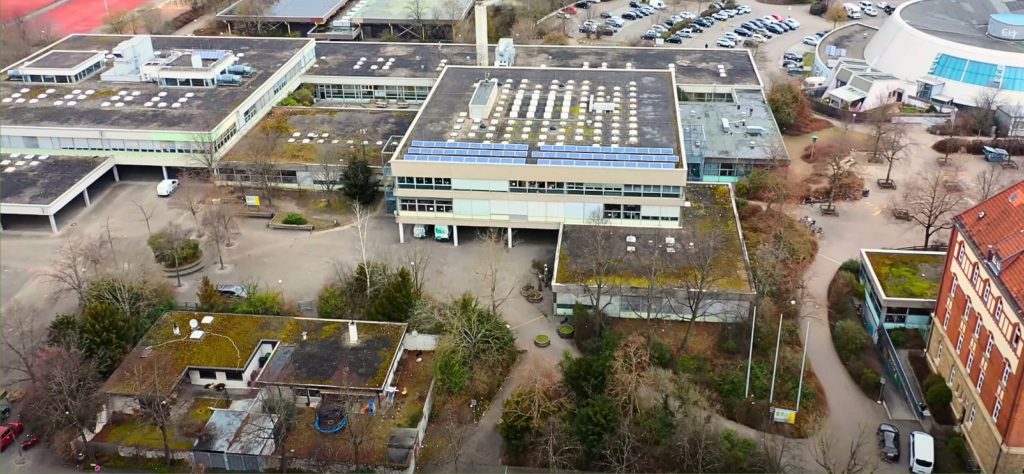 Luftaufnahme der Gottlieb-Daimler Realschule. Großes, graue Gebäude mit mehreren Abschnitten und Flachdach