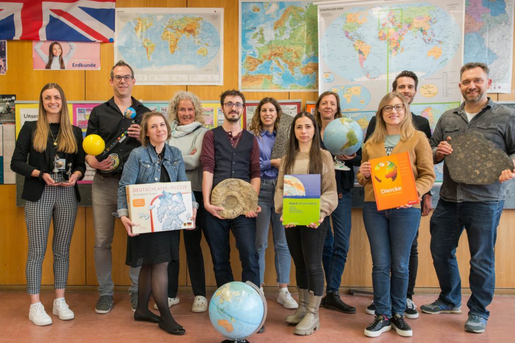 Die Geographie Lehrerinnen und Lehrer halten Atlanten und Globen in der Hand